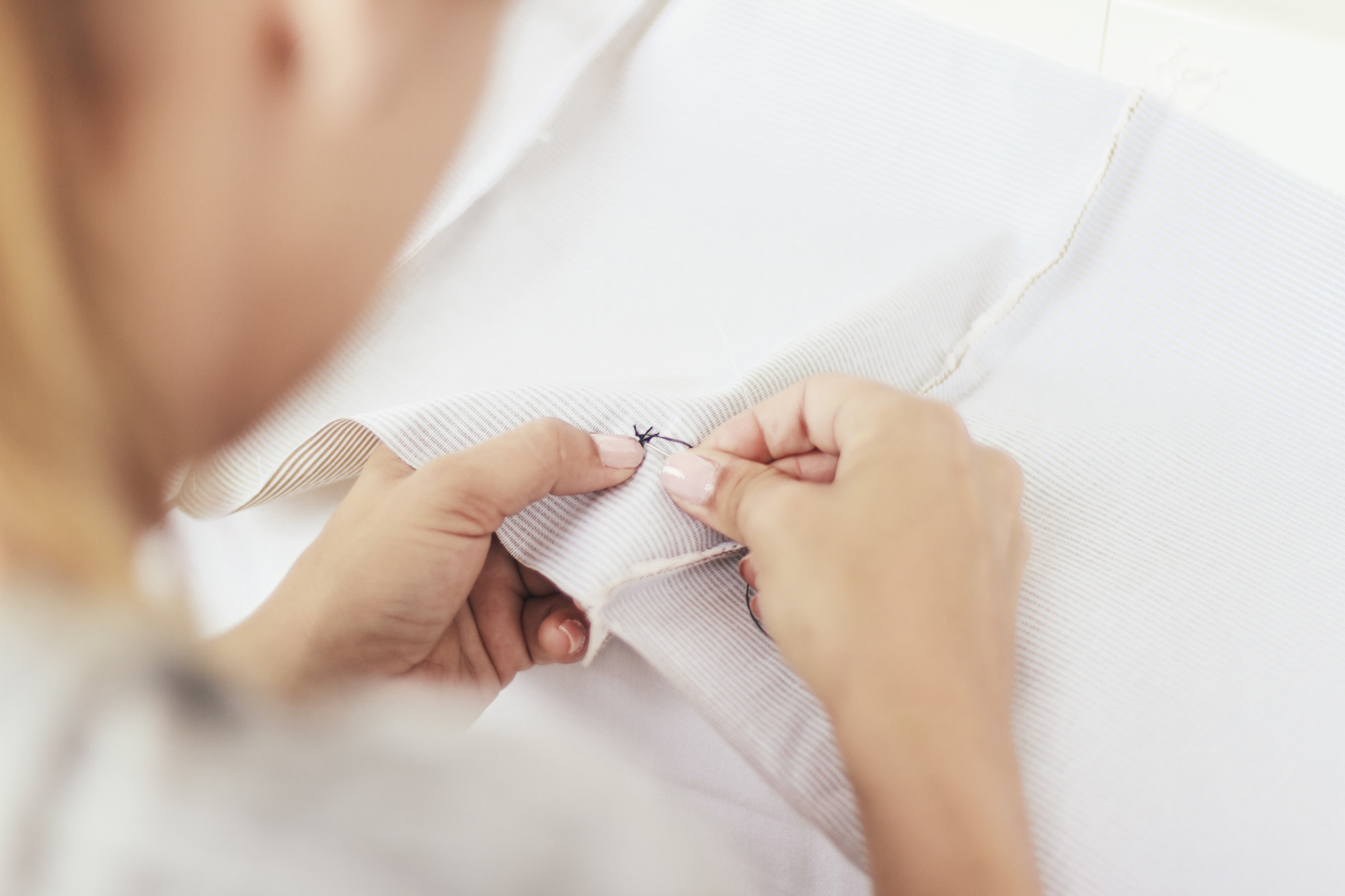 hands finishing a fine satin stitch on linen